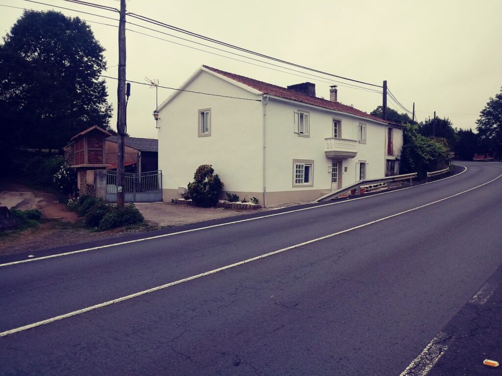 Casa encalada con hórreo e xardín